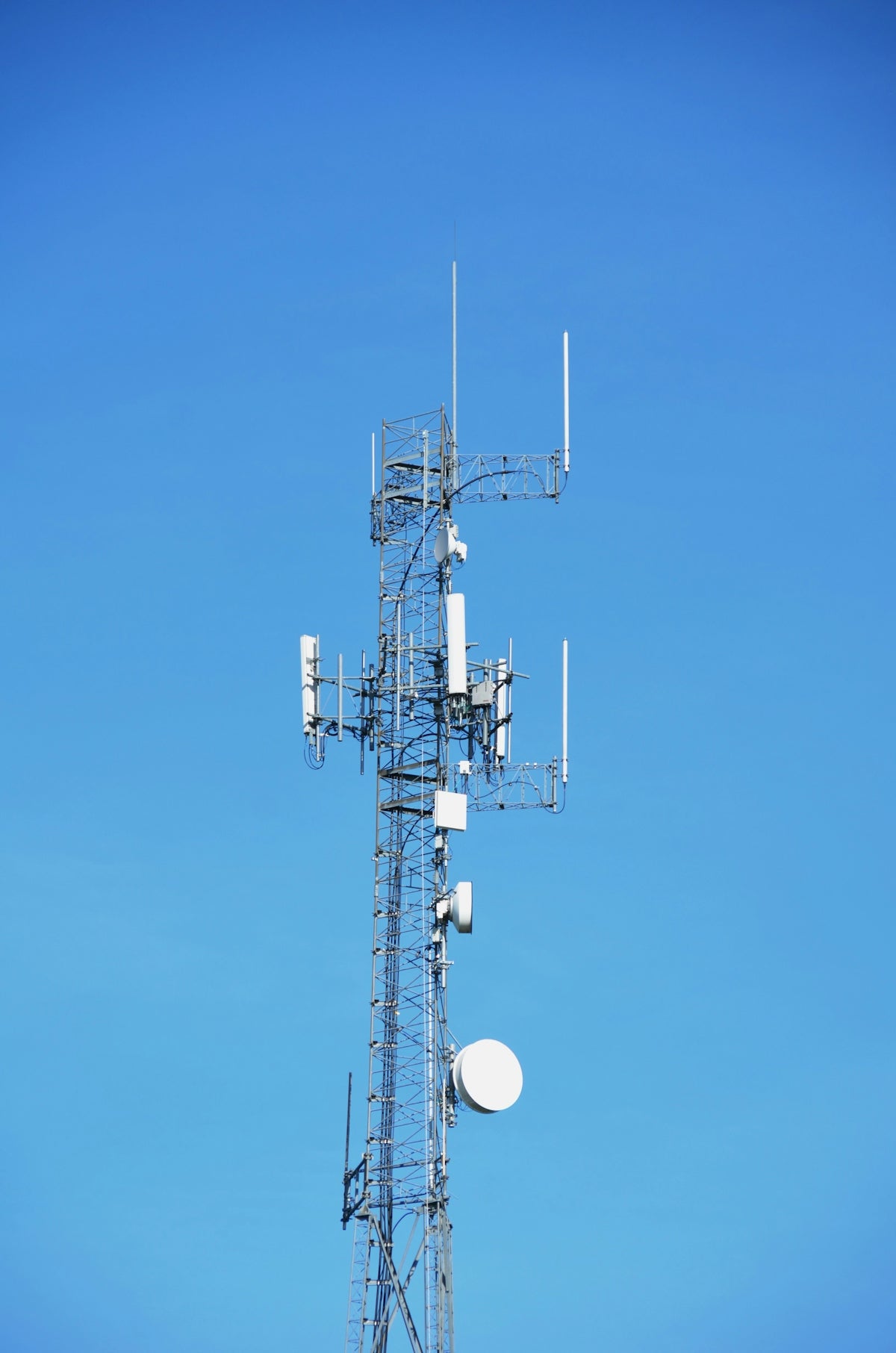 A telecommunication tower against a blue sky.