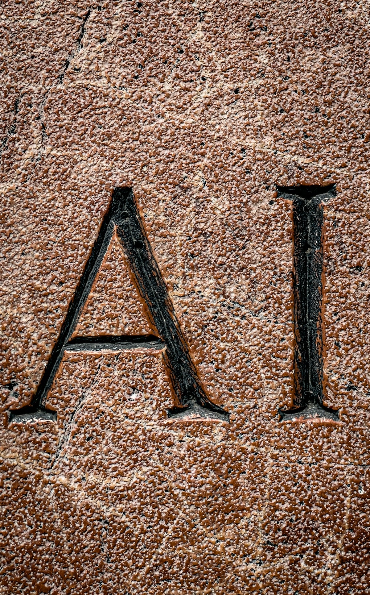 The letters ai are carved into a stone.
