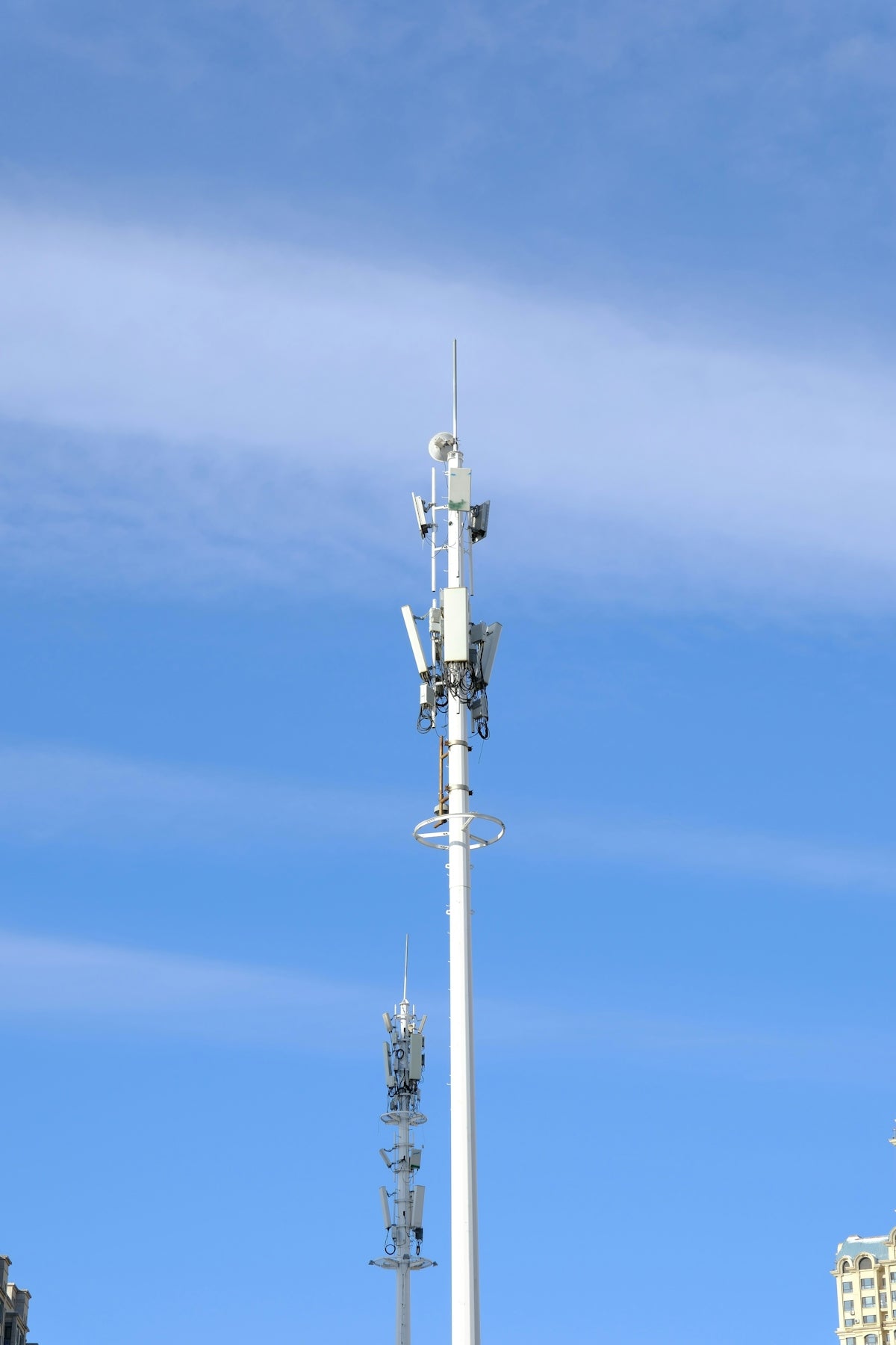 Two cell towers against a bright blue sky.