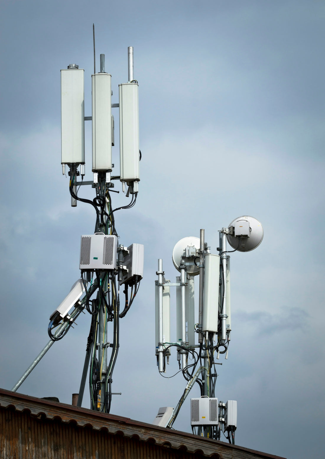 Cell towers with antennas against a cloudy sky