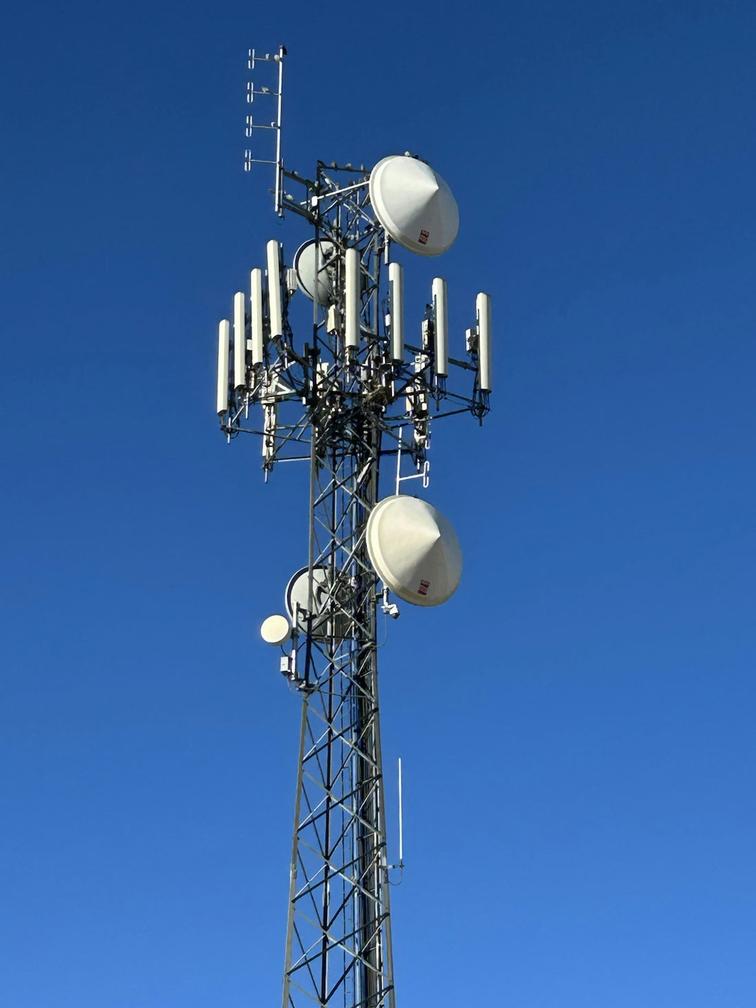 A tall telecommunications tower against a clear blue sky.