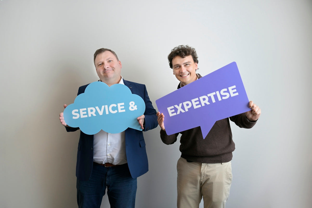 Two smiling men holding service & and expertise signs